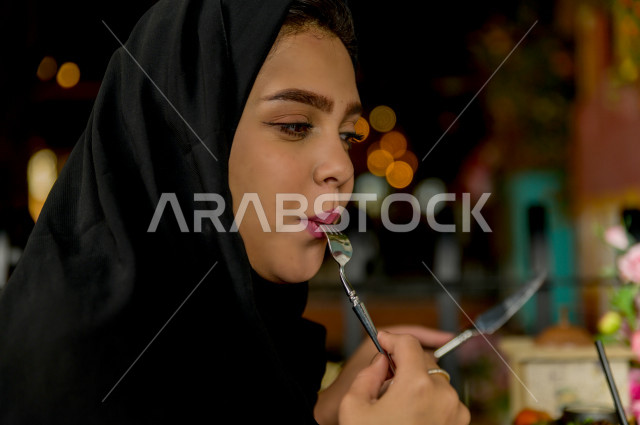 صورة مقربة لسيدة عربية خليجية سعودية تتناول الطعام في المطعم ، قضاء اجواء رائعة  في المطعم ، العديد من أصناف الطعام و الماكولات على الطاولة ، جلسات فريدة و مميزة ، مطاعم و كافيهات في السعودية