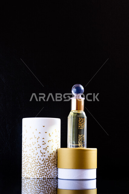 علبة من العطور الفخمة العربية الفاخرة، التعطر والتطيب بالزيوت الطبيعيه والمسك, تولة زجاجية من زيت المسك السعودي الأصلي، خلفية سوداء.