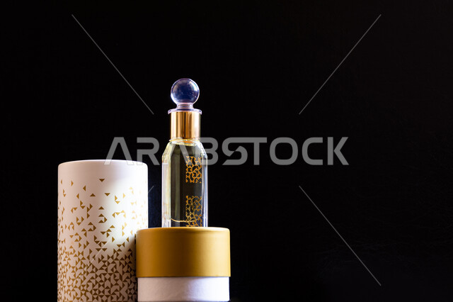 التعطر والتطيب بالزيوت الطبيعيه والمسك, تولة زجاجية من زيت المسك السعودي الأصلي، علبة من العطور الفخمة العربية الفاخرة، خلفية سوداء.