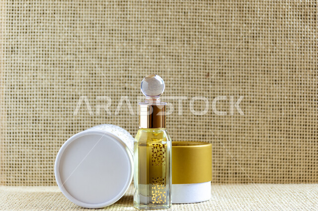 Perfume and perfume with natural oils and musk, a box of luxurious Arabic perfumes, a glass top of the original Saudi musk oil, a colored background.