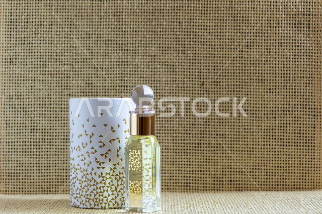 علبة من العطور العربية الفخمة الفاخرة، تولة زجاجية من زيت المسك السعودي الأصلي، التعطر والتطيب بالزيوت الطبيعيه والمسك,  خلفية ملونة .