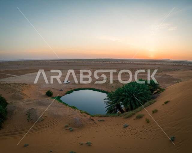 واحة برودان في منطقة نجد في مدينة الرياض وقت غروب الشمس ، بحيرة صغيرة وسط الكثبان الرملية الذهبية الناعمة ، الاماكن الطبيعية السياحية في المملكة العربية السعودية، خلفية الطبيعه
