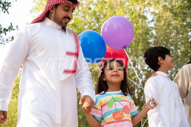 نشاطات و فعاليات ترفيهية مسلية للأطفال, قضاء أوقات ممتعة برفقة العائلة في عطلة صيفية, عائلة عربية خليجية سعودية تقوم بالتجول و المشي في الطبيعة الخضراء في إحدى حدائق المملكة العربية السعودية, حدائق ومنتزهات عائليه, خلفية طبيعة.