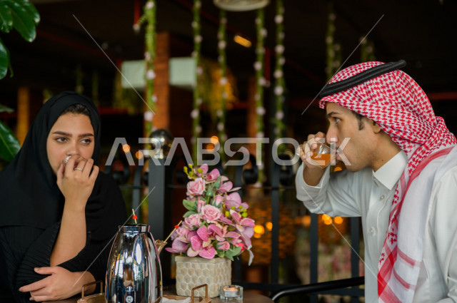 زوجان عربيان خليجيان سعوديان يجلسان في المطعم بأجواء رائعة ، يقضيان وقتهما سويا للاستمتاع و الترفيه عن انفسهم ، قضاء أوقات ترفيهية ممتعة ، جلسات فريدة و مميزة ، مطاعم و كافيهات في السعودية