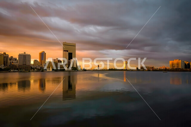 منظر السماء الملبده بالغيوم وقت غروب الشمس, انعكاس ظل المباني السكنية والتجارية على الواجهة البحرية لمدينه جدة في المملكة العربيه السعودية, التصميم الهندسي المميز للابراج وناطحات السحاب, أماكن سياحيه مشهورة, خلفيه الطبيعه