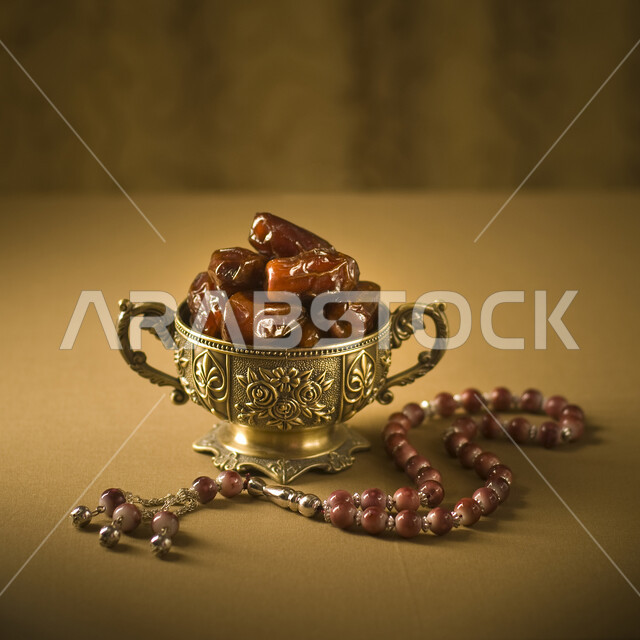 صحن مليء بالتمر السكري الرطب من نخيل المملكة العربية السعودية, صورة مقربة لوعاء من التمر المكنوز بجانبه سبحة, تمور المملكه العربيه السعوديه والمدينه المنوره، وجبة ذات قيمة غذائية عالية، ضيافة رمضانية صحية