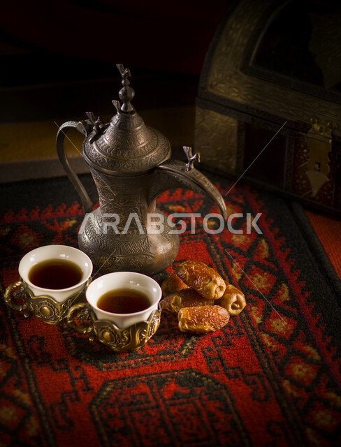 Arabic coffee dallah with two cups of coffee and a plate of dates, serving hot coffee to guests, good hospitality and reception in Saudi Arabia, honoring the guest in Ramadan, happy holidays and occasions