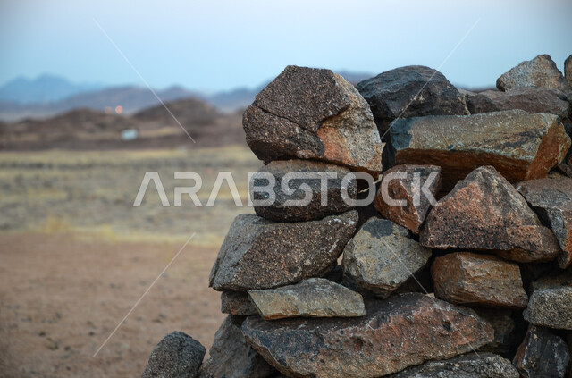 الأجواء الصيفية في البيئة الصحراوية في المملكة العربية السعودية، صورة مقربة لجدار مبني من الحجر و الصخور الطبيعية في الصحراء، نمو الأعشاب و النباتات الصحراويه في البراري، خلفية الطبيعة.