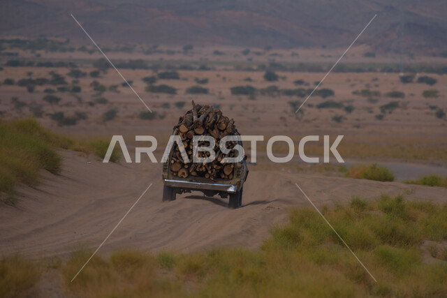 صورة من الخلف لسيارة محملة بالحطب على الطريق البري بين المملكه وقطر، المناظر الصحراويه والطبيعه الجبليه والكثبان الرمليه على طريق سلوى في المملكة العربية السعودية, الحجارة الصخرية و التلال والهضاب في المناطق الجبلية, خلفية الطبيعه