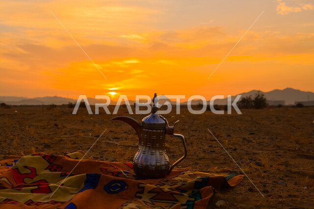 دله قهوة عربية شرقية على قطعة قماش شعبية في المناطق الصحراوية , جلسة بر شعبية في صحراء المملكة العربية السعودية, تقديم المشروبات الساخنة, الققم والمرتفعات الجبلية وقت غروب الشمس, خلفية الطبيعة