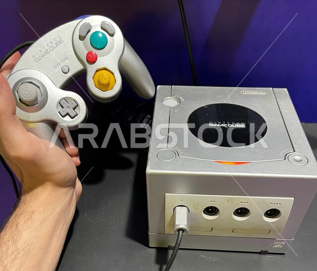 ذكريات من الماضي، صورة مقربة لجهاز مكعب الألعاب مع يد التحكم، أجهزة الألعاب الإلكترونية القديمة، التحديات و المنافسات و اللعب مع الاصدقاء و العائلة، أجهزة لعب نينتيندو، جيمز شبابية منزلية مسلية، قضاء الأوقات الممتعه في ممارسه الأنشطه الترفيهيه