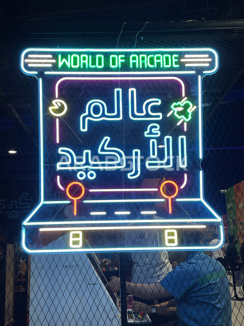 صورة مقربة للوحة إعلانية بارزة، نيون مضيء لكلمة عالم الأركيد، اللعب في صالات الألعاب الألكترونية في موسم الجيمرز ٨ في بوليفارد الرياض، قضاء أوقات ممتعة في ممارسة الأنشطة الترفيهية، التحدي والمنافسة بين اللاعبين السعوديين الخليجيين