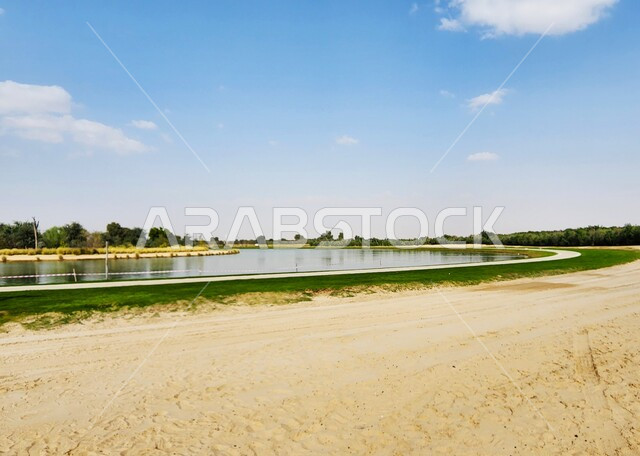 الرمال الناعمة على شاطئ بحيرة مائية صناعية في دولة قطر، الاشجار والنباتات الخضراء المحيطة بالمياه، اماكن ترفيهية سياحية في قطر