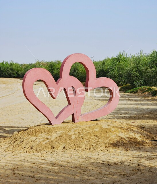 مجسم على شكل قلب فوق تل رملي في قطر، الأشجار والنباتات الطبيعية الخضراء في وضح النهار، اماكن ومعالم سياحية في دولة قطر، مجسمات قلوب مع خلفية الطبيعة