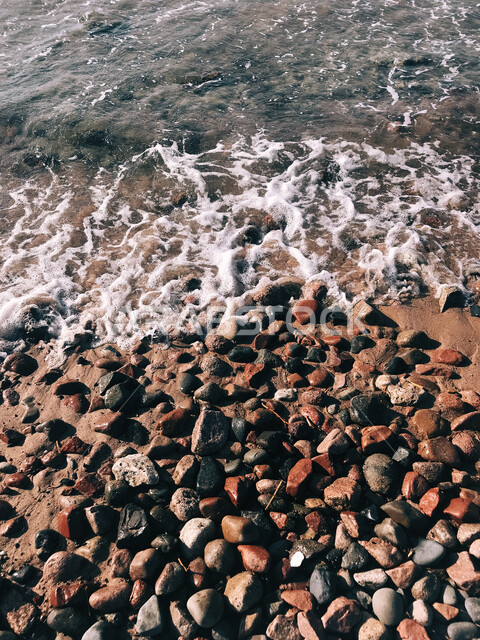 Rocky beach waves, close-up of colorful seashore stones and pebbles, water wealth and natural environment, natural tourist attractions, nature background.