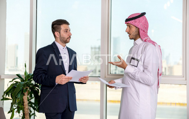رجل اعمال سعودي خليجي في مقر الشركة مع السكرتير الخاص فيه يدير المهام اليومية ،ادارة الاعمال داخل مقر الشركة ، شركاء عمل ، متابعة الاهداف والخطط ، شركة سعودية ، بيئة العمل