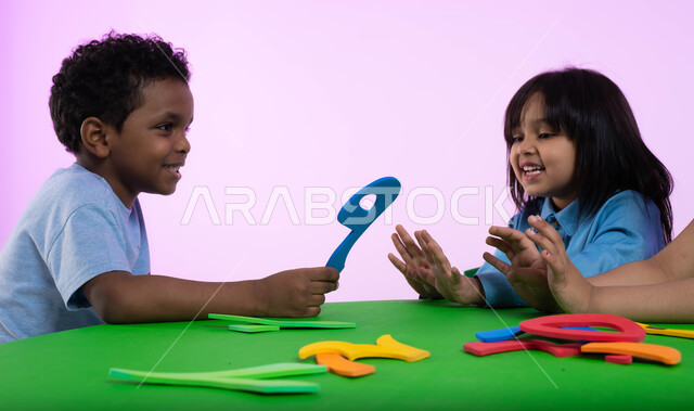  تعلم الأرقام والأعداد العربية وأشكالها، نشاطات ترفيهية وتعليمية تساعد على تنمية القدرات الفكرية، المشاركة والتعاون بين أطفال الروضة في تعلم الرياضيات، بوتريه مقرب لأطفال عرب خليجيين سعوديين يرتدون الزي الكاجوال يتعلمون الحساب، خلفية وردية.