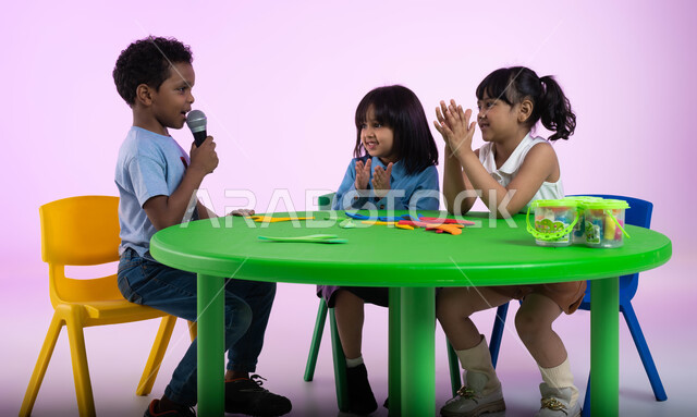 موهبة الغناء والتدريب الصوتي، إيماءات الإندماج والتفاعل مع الموسيقا، بورتريه لأطفال عرب خليجيين سعوديين يرتدون الزي الكاجوال يستمتعون بالغناء والتصفيق، تقديم العروض الفنيه المسرحيه الغنائيه، تسجيل مقطع صوتي غنائي، تنمية مواهب الأطفال في الروضة، خلفيه وردي