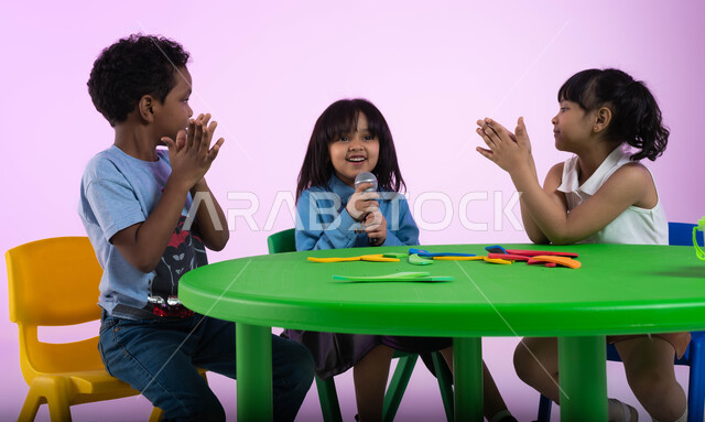 إيماءات الإندماج والتفاعل مع الموسيقا، موهبة الغناء والتدريب الصوتي، بورتريه لأطفال عرب خليجيين سعوديين يرتدون الزي الكاجوال يستمتعون بالغناء والتصفيق، تقديم العروض الفنيه المسرحيه الغنائيه، تسجيل مقطع صوتي غنائي، تنمية مواهب الأطفال في الروضة، خلفيه وردي