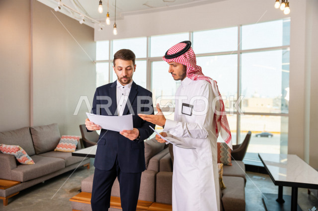 رجل اعمال سعودي خليجي في مقر الشركة مع السكرتير الخاص فيه يدير المهام اليومية ،ادارة الاعمال داخل مقر الشركة ، شركاء عمل ، متابعة الاهداف والخطط ، شركة سعودية ، بيئة العمل