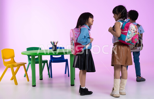 تنمية مهارات وتعليم وإبداع في الروضات العربية الخليجية السعودية، الاستعداد والتجهيز للعودة إلى المنزل، بورتريه لأطفال عرب خليجيين سعوديين يرتدون الزي الكاجوال وحقيبة الظهر، إيماءات تدل على الفرح والسعادة، خلفية وردية.