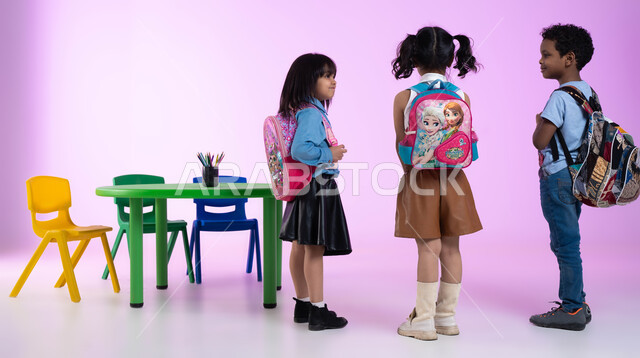تعليم وإبداع وتنمية مهارات الأولاد في الروضة، الاستعداد والتجهيز للعودة إلى المنزل، بورتريه لأطفال عرب خليجيين سعوديين يرتدون الزي الكاجوال وحقيبة الظهر، إيماءات تدل على الفرح والسعادة، خلفية وردية.
