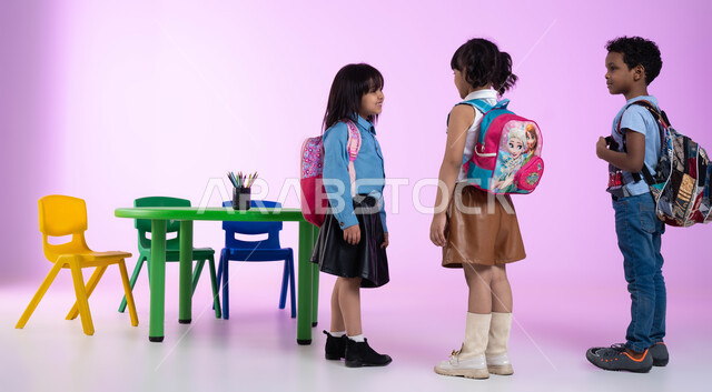 Getting ready and preparing to go home, teaching, creativity and developing the skills of kindergarten boys, a portrait of Saudi Gulf Arab children wearing casual clothes and a backpack, gestures indicating joy and happiness, a pink background.