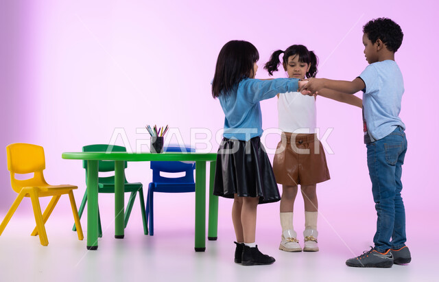 دمج المتعة والفائدة في الروضة، تعليم وإبداع وتنمية مهارات في رياض الأطفال، بورتريه لأطفال عرب خليجيين سعوديين يرتدون الزي الكاجوال يلعبون ويمرحون، إيماءات تدل على الفرح والسعادة، خلفية وردية.