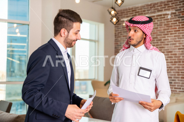 رجل اعمال سعودي خليجي في مقر الشركة مع السكرتير الخاص فيه يدير المهام اليومية ،ادارة الاعمال داخل مقر الشركة ، شركاء عمل ، متابعة الاهداف والخطط ، شركة سعودية ، بيئة العمل