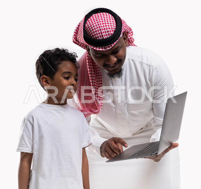 التسويق الالكتروني المنزلي، متابعة الأفلام الكرتونية المفضلة، التعليم عن بعد، بورتريه لولد عربي خليجي سعودي بجانب والده يتابع حصص الأونلاين عبر جهاز الحاسوب، الاهتمام والاعتناء بالأبناء، أخبار جديده على مواقع التواصل الاجتماعي، خلفية بيضاء
