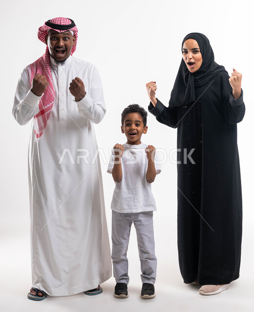 المنتخب الوطني السعودي، الشغف في متابعة فريق كرة القدم, ايماءات السعادة بالفوز والانتصار و الكسب، أندية وتشجييع, بورتريه لعائلة عربية خليجية سعودية تشاهد مباريات كرة القدم ، قضاء أوقات ممتعه مع الأهل والأبناء، صورة الجسم بالطول الكامل ،خلفية بيضاء