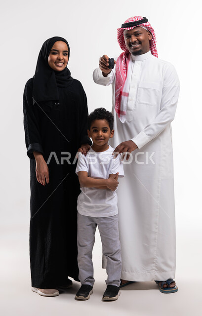 الحصول على رخصة القيادة، بورتريه مقرب لعائلة عربيه خليجية سعودية تجلس على كنبه رمادية في غرفة المعيشة، ايماءات تدل على السعادة فرحا في اقتناء سيارة جديدة، أساسيات العائلة السعوديه السعيده، صورة الجسم بالطول الكامل، خلفية بيضاء