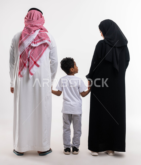 بناء مجتمع سعودي متنامي، قضاء الوقت مع الأهل والأبناء ،بورتريه من الخلف لعائله عربيه سعوديه خليجيه مكونه من الاب والام والابن، المحافظة على ترابط الاسرة، الحياة الزوجية الناجحة, صورة الجسم بالطول الكامل، خلفية بيضاء