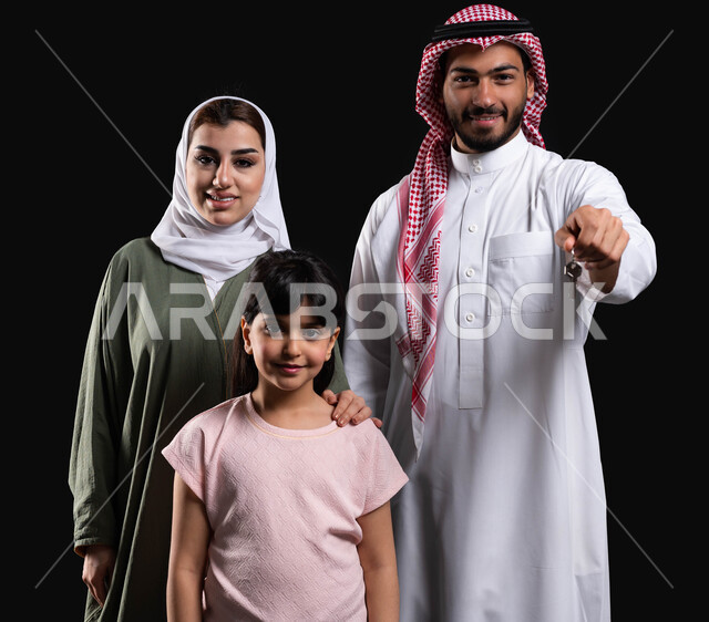 الإهتمام والإعتناء بالعائلة، بورتريه لرجل عربي سعودي خليجي مع عائلته يشير بأصبع السبابة نحو شيء ما، المحافظة على الترابط الأسري والإستقرار العائلي، إيماءات اللمس والضغط، الأجواء العائلية المليئة بالحب، حركة أصبع وإشارات، خلفية سوداء