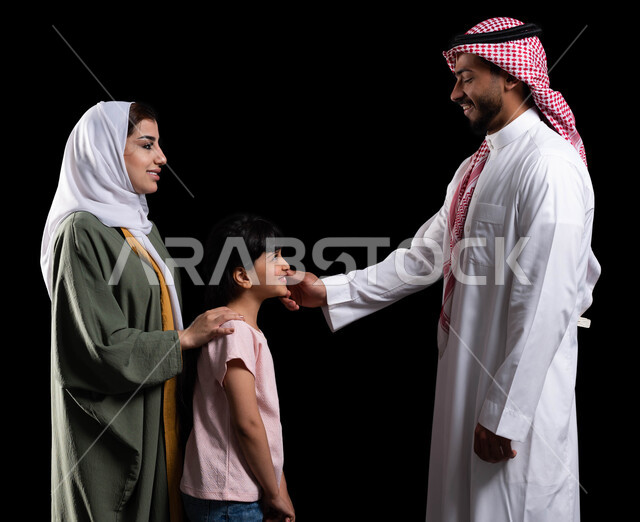 الترابط الأسري والمحافظة على أمان وإستقرار العائلة، بورتريه لرجل سعودي خليجي عربي برفقة عائلته يقوم بمداعبة ابنته، مفهوم الإهتمام والإعتناء بالأبناء، الأجواء العائلية المليئة بالحب، إيماءات السعادة والبهجة والسرور، خلفية سوداء