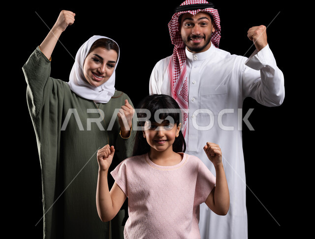 إيماءات الفوز والنجاح والإنتصار وتحقيق الأهداف، بورتريه لعائلة عربية خليجية سعودية تقوم برفع يدها لأعلى بحماس، الترابط الأسري والمحافظة على الأمان والإستقرار العائلي، قضاء أوقات عائلية ممتعة ومليئة بالحب، خلفية سوداء