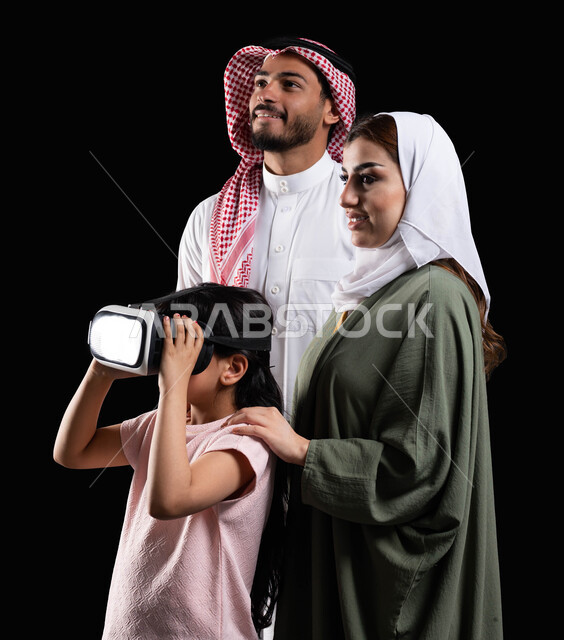 الإستمتاع بمشاهدة الأفلام ومحاكاة العالم الإفتراضي، مفهوم الإهتمام والإعتناء بالأبناء، أنشطة تقنية ترفيهية مسلية، بورتريه لفتاة عربية سعودية خليجية برفقة والديها ترتدي نظارات الواقع الإفتراضي (في آر) ثلاثية الإبعاد، خلفية سوداء