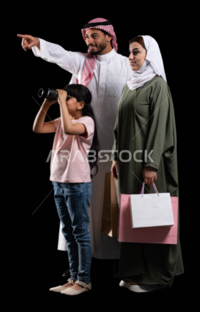 البحث والتخطيط والنظر للمستقبل، بورتريه لفتاة عربية خليجية سعودية رفقة والديها تنظر من خلال الناظور لرؤية الأشياء البعيدة، أب يشير نحو شيء ما بهدف لفت الإنتباه، الإستكشاف والمغامرة مع فريق الكشافة، صورة الجسم بالطول الكامل، خلفية سوداء