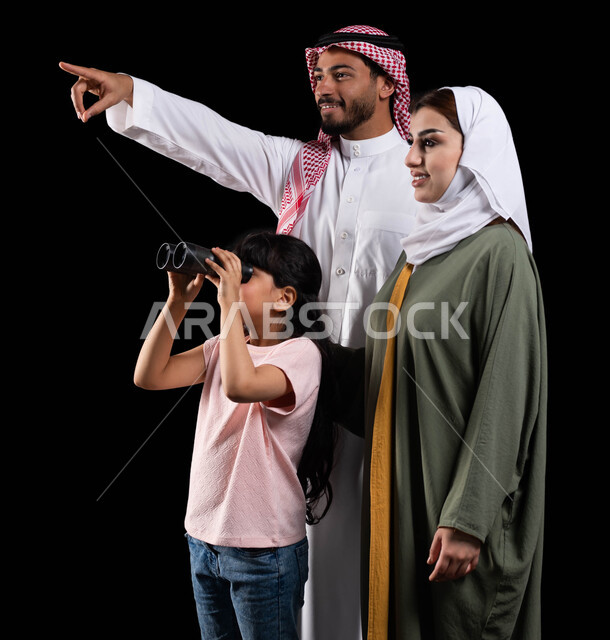 تشجيع الأهل للأبناء على الإستكشاف والمغامرة، بورتريه لفتاة عربية خليجية سعودية رفقة والديها تنظر من خلال الناظور لرؤية الأشياء البعيدة، أب يشير نحو شيء ما بهدف لفت الإنتباه، المحافظة على الترابط الأسري، البحث والتخطيط والنظر للمستقبل، خلفية سوداء