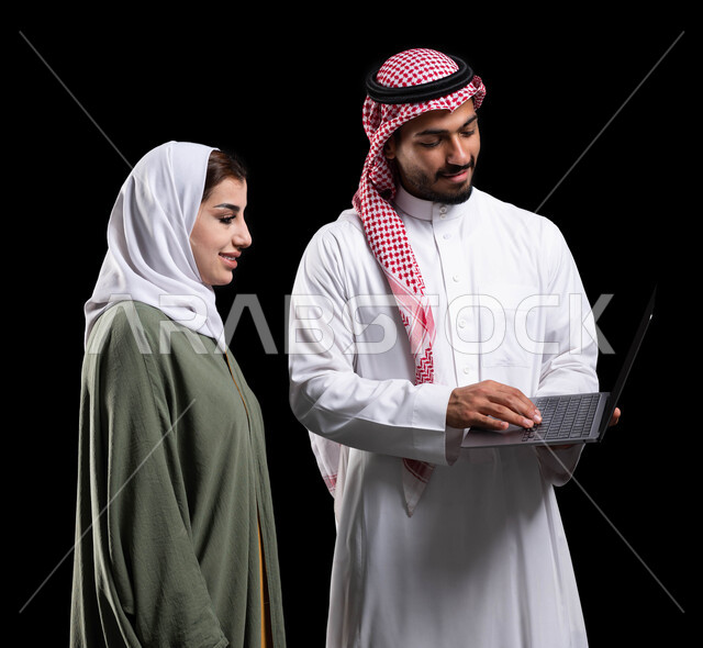 دراسة وتحليل المشاريع الجديدة، النظر  إلى شيء ما في الحاسوب, الشراكة والتعاون في إنجاز المهام، بورتريه لمرأة عربية خليجية سعودية و رجل عربي خليجي سعودي في اجتماع عمل، استخدام جهاز الحاسوب المحمول لمتابعة ومناقشة الأعمال، فريق يقوم باجتماع عمل, خلفية سوداء