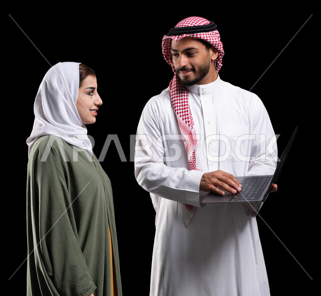 الشراكة والتعاون في إنجاز المهام، بورتريه لمرأة عربية خليجية سعودية و رجل عربي خليجي سعودي في اجتماع عمل، استخدام جهاز الحاسوب المحمول لمتابعة ومناقشة الأعمال، دراسة وتحليل المشاريع الجديدة، فريق عربي خليجي سعودي يقوم باجتماع عمل, خلفية سوداء