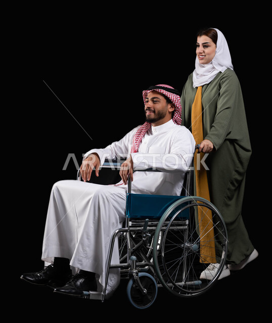 ايماءات النظر إلى شيء ما, الإخلاص والعطف والحنان بين الأزواج, شعور المعاقين بالإنتماء والتقدير والإحترام في السعوديه، زوجة عربية خليجية سعودية محجبة ترتدي العباءة تقوم بمساعدة زوجها من ذوي الاحتياجات الخاصه، خلفية سوداء