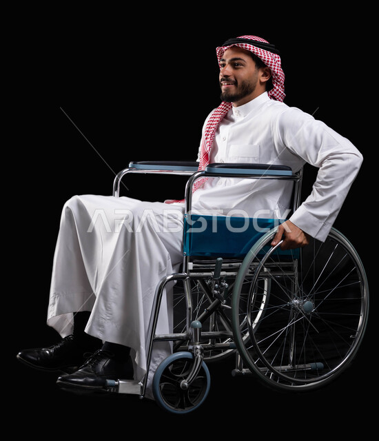 Gestures of happiness and optimism in the future life, maintaining activity and physical health by moving the hands during movement, a smiling Saudi Arabian man sitting in a wheelchair, using wheelchairs for people with disabilities to help move and move