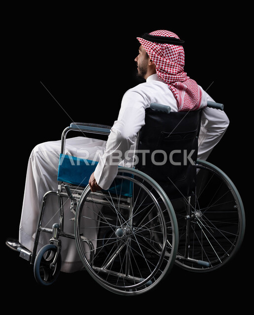 استخدام كراسي المعاقين للمساعده على الحركه والتنقل, تحسين جودة حياة ذوي الاعاقه الحركيه, الحفاظ على الصحة البدنية من خلال تحريك اليدين أثناء الحركة, رجل عربي خليجي سعودي يرتدي الثوب التقليدي مقعد على كرسي متحرك, خلفية سوداء