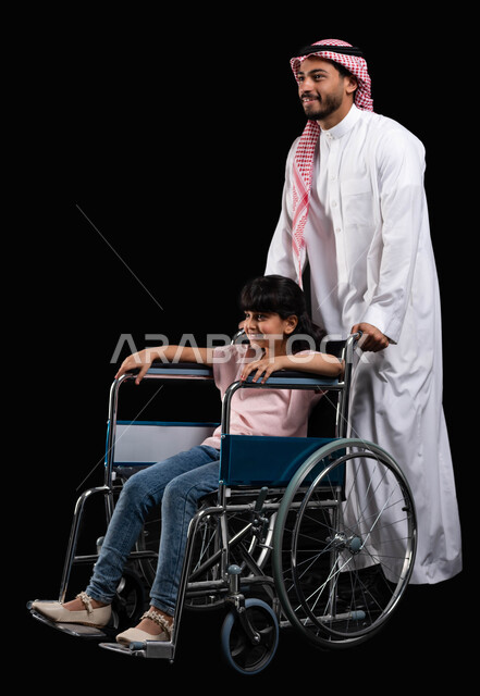 مفهوم الاهتمام بالجانب النفسي والجسدي لأصحاب الهمم, رعاية الأبناء والاعتناء بالمرضى المعاقين, بورتريه لأب عربي سعودي خليجي يقوم بمساعدة ابنته على الكرسي المتحرك, الاهتمام بذوي الاحتياجات الخاصة بايماءات البشاشة والمعاملة الحسنة, خلفية سوداء