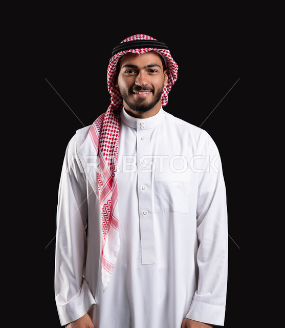 الإعتناء بالمظهر الخارجي، ايماءات وجه تدل على الفرح والسعاده، بورتريه مقرب لرجل عربي خليجي سعودي يرتدي الشماغ والثوب التقليدي يبتسم ويقوم بالنظر إلى الكاميرا، خلفيه سوداء.