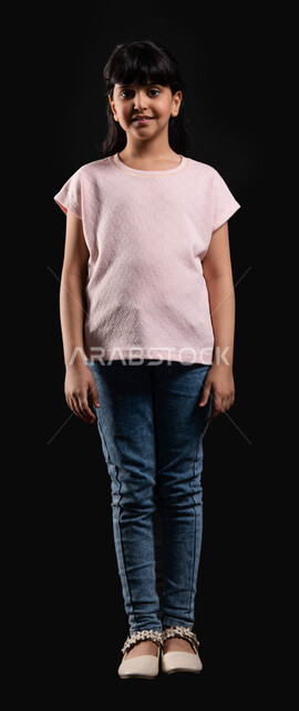 الوقوف أمام الكاميرا والنظر بثقه إستعدادا لإلتقاط صوره تذكاريه، بورتريه لفتاة عربيه خليجيه سعوديه مبتسمه ترتدي الزي الكاجوال، ايماءات وتعابير وجه تدل على السعاده والسرور، صوره الجسم بالطول الكامل، خلفيه سوداء.