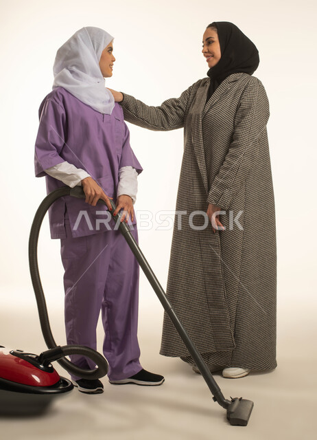 توفير خدمات العناية بالمنزل، المعاملة الحسنة للخادمات، بورتريه لسيدة عربية خليجية سعودية تشكر العاملة المنزلية على الاهتمام بالنظافة وجودة العمل، خادمة افريقية تقوم باستخدام المكنسة الكهربائية، استقدام العمالة الخارجية المرخصة والمؤهلة، خلفية بيضاء