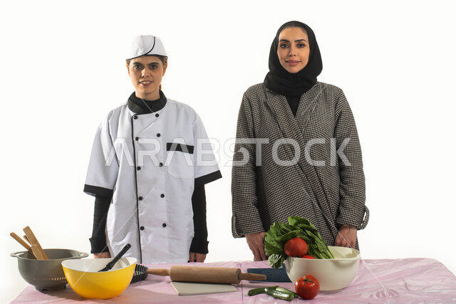 Preparing delicious food and dishes, popular recipes and dishes, training domestic workers on the traditional Saudi cooking method, a portrait of a cook practicing the profession of cooking in the house of a veiled Saudi Arab Gulf woman, looking at the ca