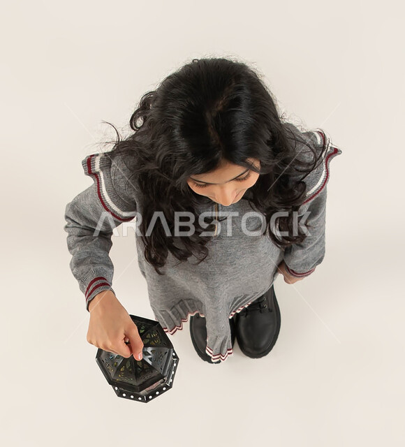 التحضيرات لاستقبال شهر رمضان المبارك، بورتريه علوي عامودي لبنت عربيه خليجيه سعوديه تحمل بيدها الفانوس الرمضاني، المناسبات الدينيه والأعياد الإسلامية، التزيين والتجهيز للأجواء الروحانيه الرمضانيه، اسلاميات و عبادة، خلفيه بيضاء.